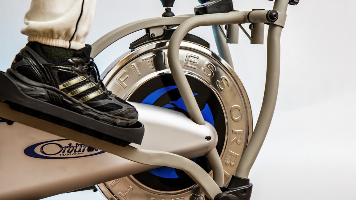 Foot on pedal of elliptical trainer showcasing fitness equipment and footwear close-up.